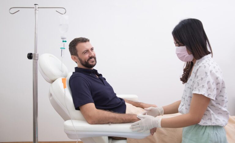 Young man receiving vitamin IV infusion drip in hospital or beauty salon. Healthcare, wellness and medicine concept.